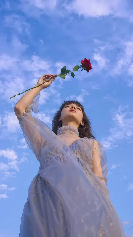 Dreamy Girl Holding a Red Rose Against Blue Sky Aesthetic Portrait Photography